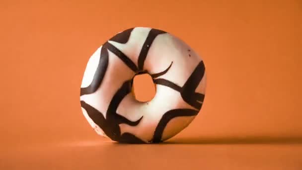 黑白色巧克力甜甜圈 橙色背景下旋转 — 图库视频影像