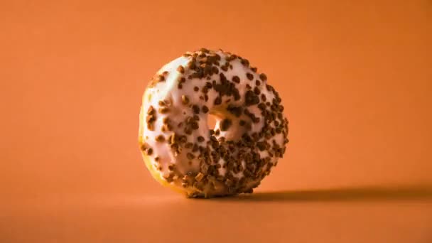Witte Chocolade Donut Met Amandelen Topping Roteren Oranje Achtergrond — Stockvideo