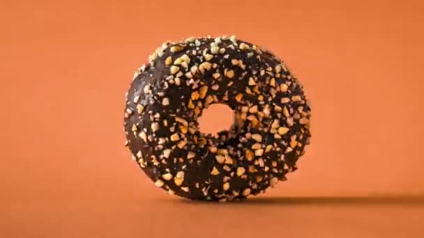 Schokoladen Donut Mit Mandelbelag Der Rotierend Auf Orangefarbenem Hintergrund Ein — Stockvideo