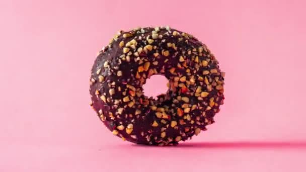 Schokoladen Donut Mit Mandelbelag Der Rotierend Auf Rosa Hintergrund Herangezoomt — Stockvideo