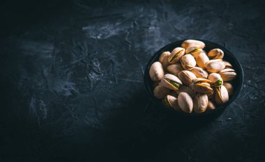 Karanlık bir masada, karanlık bir kasede fıstıklar. Fındık yemeye hazır. Enerji gıdası. 