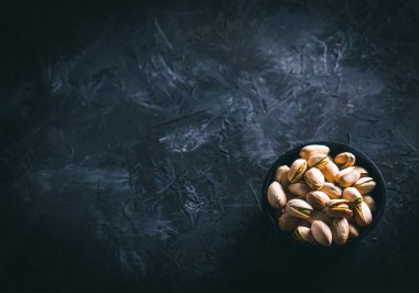 Karanlık bir masada, karanlık bir kasede fıstıklar. Fındık yemeye hazır. Enerji gıdası. 