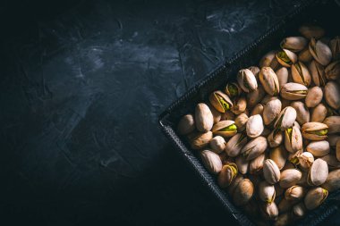 Karanlık bir masada, karanlık bir kasede fıstıklar. Fındık yemeye hazır. Enerji gıdası. 