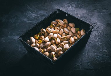 Karanlık bir masada, karanlık bir kasede fıstıklar. Fındık yemeye hazır. Enerji gıdası. 