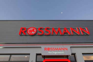 Wolfschlugen, Almanya - Kasım 06, 2020: Rossmann eczanesinin kırmızı harflerine göre, ay sabahın erken saatlerinde gökyüzünde..