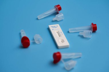 Antijen testi aynı zamanda test kaseti ve mavi bir yüzey üzerinde tüp ile Corona hızlı testi. Mavi Covid-19 harflerine odaklan. Yakın çekim..
