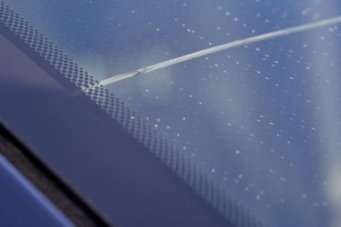 Arabanın ön camında 1 hasar var. Dolu ya da taş çarpması sonucu oluşmuş. Sigorta talebi. - Yakın çekim. Yan görünüm.