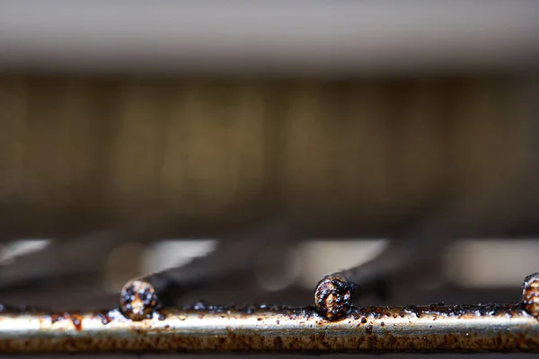 Önden yağlı ızgara paslanmış. Arkaplanda tel fırçası bulanıklaştı. Kapat..