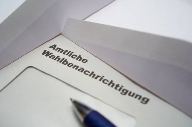 Beyaz zarfın üzerine siyah harfler: Resmi seçim bildirimi (Almanca: Amtliche Wahlbenachrichtigung). Almanya 'da 2021 federal seçimleri. Yanında iki tane açık zarf var. Çapraz görünüm.