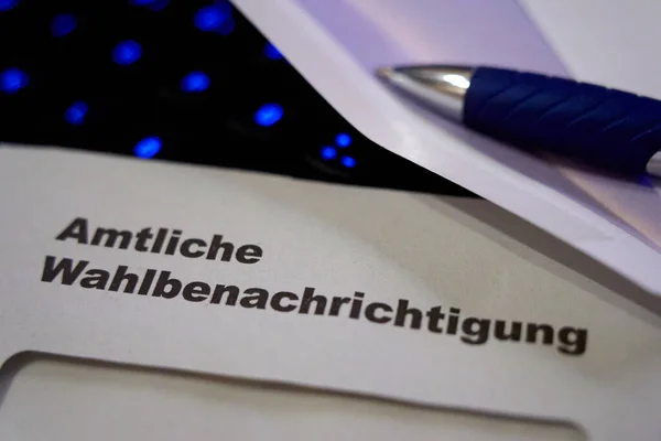 Beyaz zarfın üzerine siyah harfler: Resmi seçim bildirimi (Almanca: Amtliche Wahlbenachrichtigung). Siyah klavye arka planda mavi parlıyor. Almanya 'da 2021 federal seçimleri. Yakın çekim..