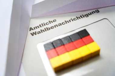 Beyaz zarfın üzerine siyah harfler: Resmi seçim bildirimi (Almanca: Amtliche Wahlbenachrichtigung). Tahta zar Alman ulusal bayrağını şekillendirir. Almanya 'da 2021 federal seçimleri. Yakın çekim..