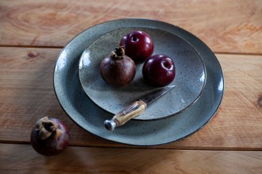 Mor erikler, mangosens ve ahşap masadaki seramik tabakta bıçak.