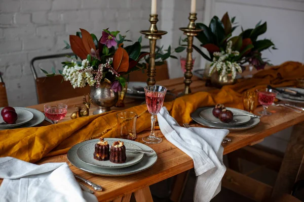 おしゃれな装飾が施された長い木製のパーティーテーブル キャンドルスティック 花の花瓶 ワインとグラス プレート 白いレンガの壁がある部屋の食べ物 — ストック写真