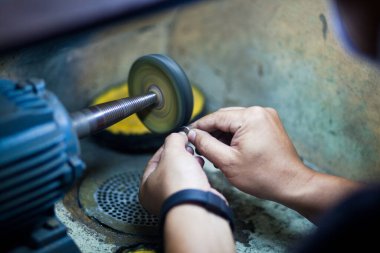 Profesyonel aletlerle mücevher yapmak için çalışma masası. Mücevher ustası elle cilalıyor.