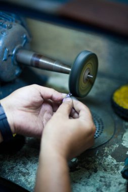 Profesyonel aletlerle mücevher yapmak için çalışma masası. Mücevher ustası elle cilalıyor.