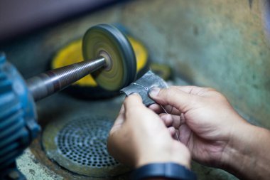 Profesyonel aletlerle mücevher yapmak için çalışma masası. Mücevher ustası elle cilalıyor.