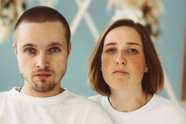 Güzel görünümlü, çekici, çekici, odaklanmış, beyaz tişörtlü, sakin bir genç adam ve kadının yakın plan portresi.