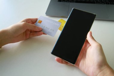 Dükkandaki ürünleri müşterilere almak için akıllı telefon kullanan bir adam. Kredi kartıyla harcama kavramı.