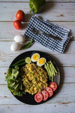 Yumurta dilimleri ve sebzelerin arka plandaki tabakta dikey üst görünümü.