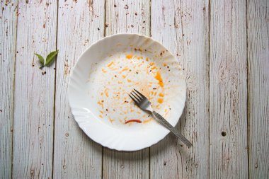 Çatalla arka planda kullanılan boş tabağın üst görünümü.