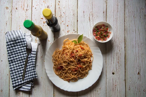 Soslu ve fesleğenli spagetti ve arka planda baharatlar.