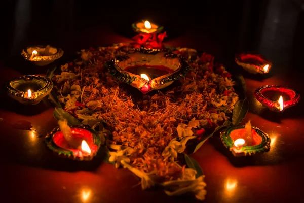 Arrangement of burning lamps and flower petals for Diwali celebrations with use of selective focus.