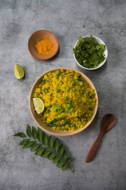 Kişniş yaprakları ve zerdeçal tozu çeşni olarak seçici odaklı bir kap poha ile birlikte..