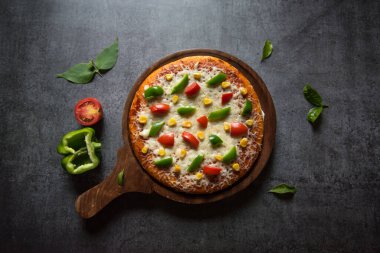 Arka planda sebzeli ve otlu İtalyan pizza manzarası.