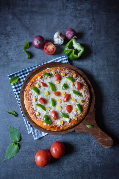 Domatesli ve ahşap tabakta mozzarella soslu popüler pizzanın dikey görüntüsü