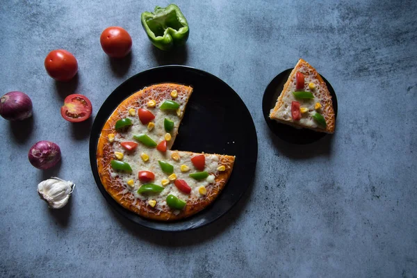 Pizzanın yukarıdan görünüşü ve içinde malzemelerle birlikte servis edilen bir dilim pizza..