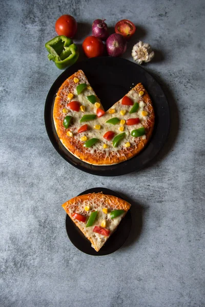 Tabakta servis edilen bir dilim pizzanın malzemeleriyle birlikte üst görüntüsü..