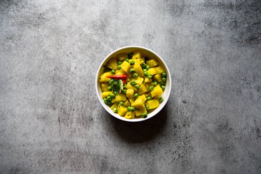 Arka planda bir kasede patatesli kişniş yaprağı..