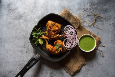 Tavuk tandırının üstündeki kişniş yaprağının ve seçici bir odak noktası olan baharatların görüntüsünü görüntüle 