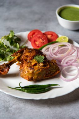 Kişniş yaprağını tavuk tandoori bacağının üzerine, seçici odaklı bir tabağın üzerine koy..