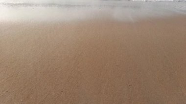 Deniz dalgaları köpüklü kabarcıklar ve dalgalarla kumu sallıyor..