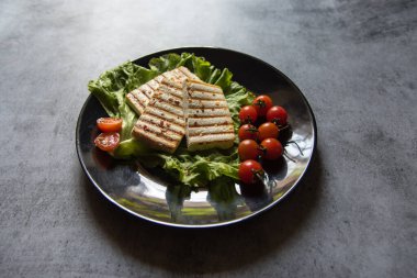 Slabs of cheesy paneer or cottage cheese along with grilled vegetables on a plate