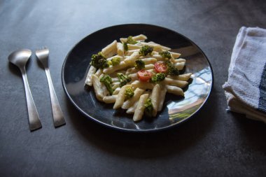  Italian food pasta with spinach, cherry tomatoes and broccoli along with fork and spoon