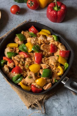 Seçici odaklı siyah bir tavada tavuk parçaları ve dolma biber..