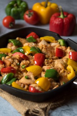  Seçici odaklı bir tavaya doğranmış tavuk parçaları ve dolmalık biber koy..