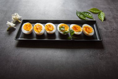 Haşlanmış yumurta dilimleri seçici bir odak ile siyah bir tepside dizilmiştir..