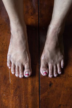 Seçici bir odak noktası olan, tahta arka planda çıplak ayaklı bir kadının en üst görünümü.