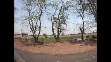 Hindistan kırsalından hızla geçen bir araçtan. Yolcuların bakış açısı. Seçici odak.