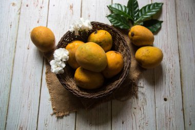 Tahta bir sepetin içindeki mangolar seçici bir odak kullanıyor.