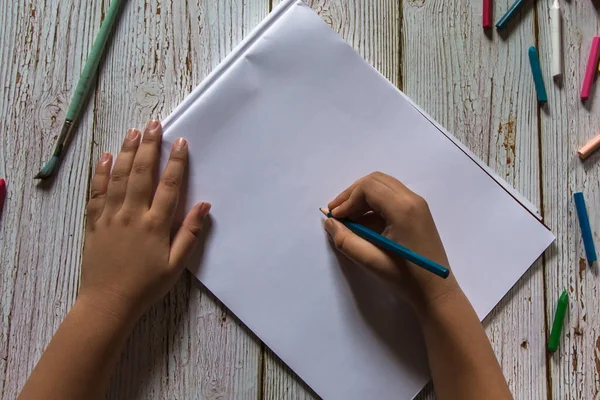 Hand of a boy holding a pencil with use of selective focus. Top view