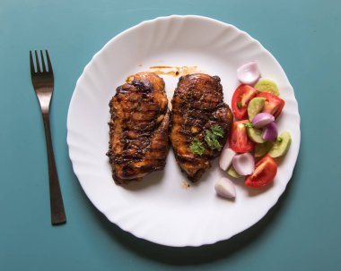 Tahta bir arka planda beyaz bir tabakta ızgara biftek ve sebze.