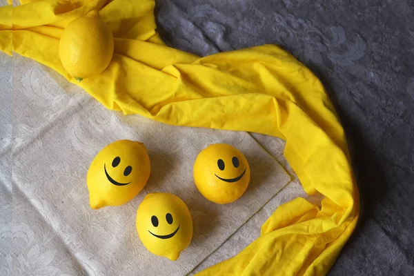 Positive emotion. Yellow lemon  with funny faces on a table.