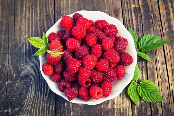 Skål Med Färska Hallon Med Gröna Blad Blå Röd Bakgrund — Stockfoto