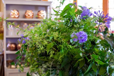 Mor çiçeklerle, yeşil yapraklarla ve okaliptüslerle ahşap masada çiçek aranjmanı