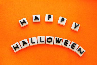 Turuncu arka planda siyah köpüklü harflerle Mutlu Cadılar Bayramı beyaz blokları