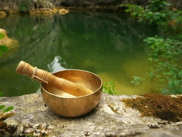 Arka planda nehir varken doğaya yerleştirilmiş şarkı kasesi.